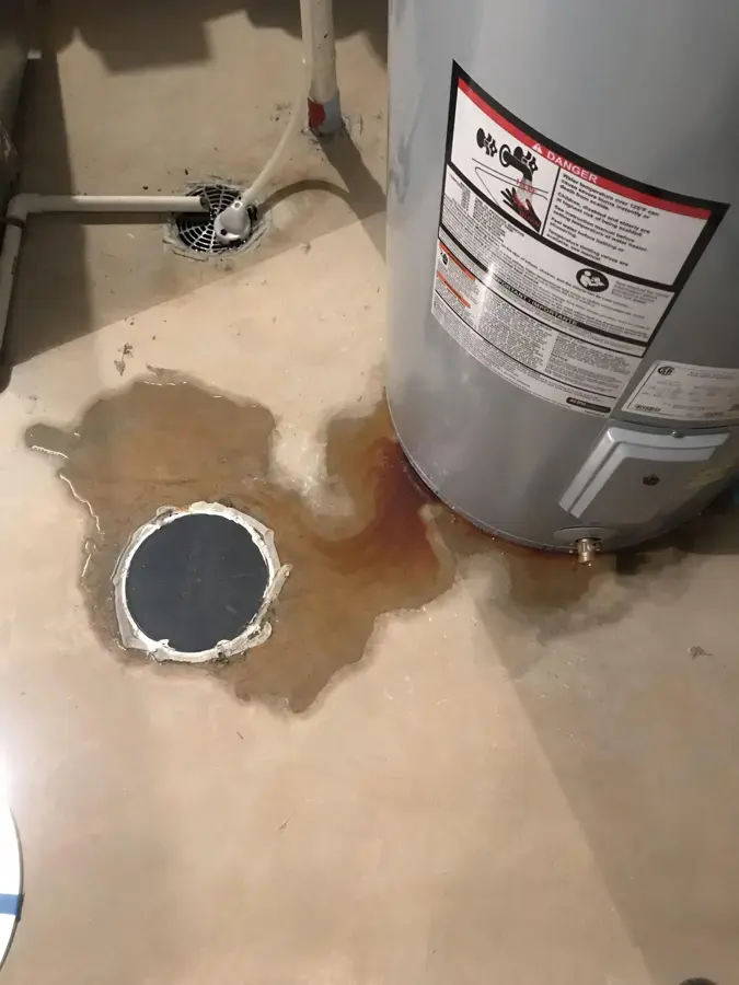 Water pooled around the base of a water heater and a floor drain