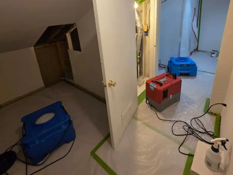 Dehumidifier and air movers drying a hallway and a closet under the stairs
