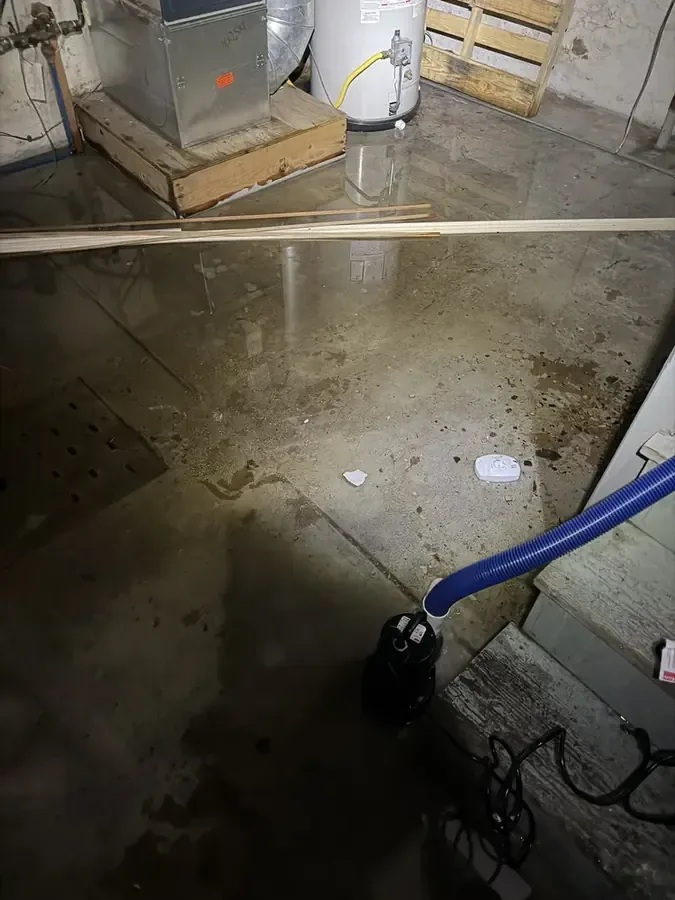 Standing water on a utility room floor beside a pump hose