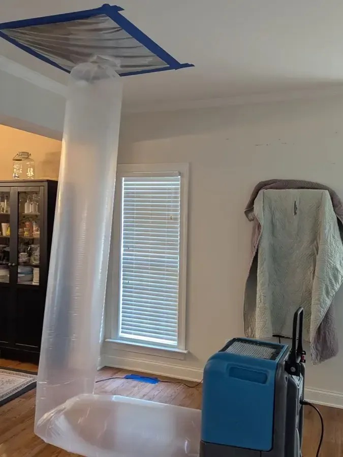 Containment tube and dehumidifier drying a wet ceiling in a living room