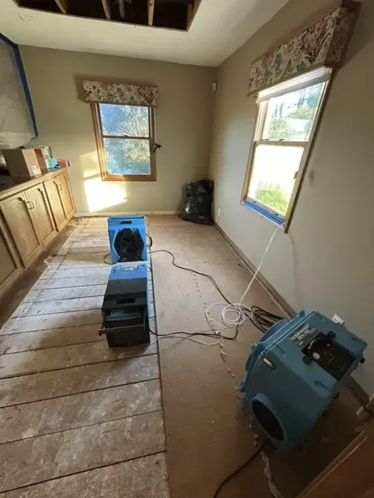 Air mover and dehumidifier on exposed bedroom floorboards