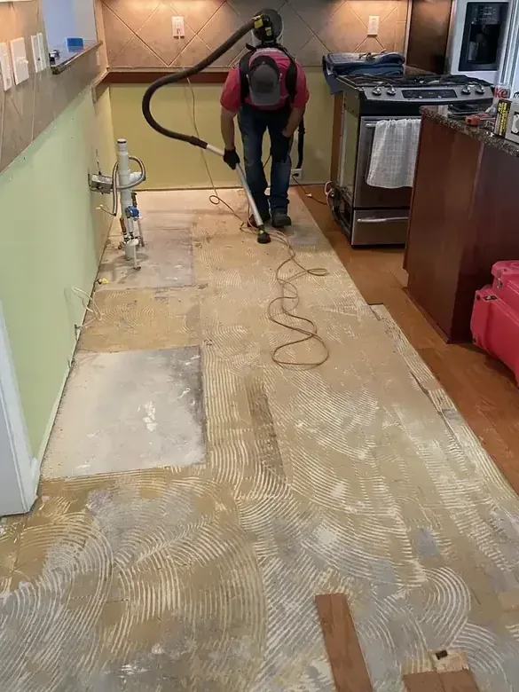Extraction hose clearing water from a kitchen floor after the flooring came up