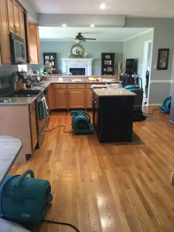 Air movers drying a kitchen and hardwood floor after a leak
