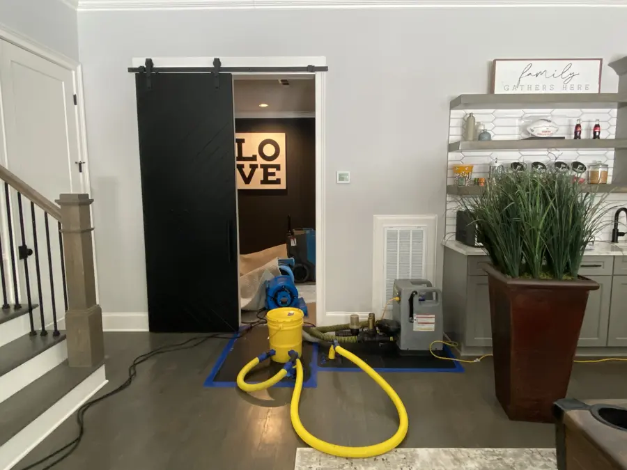 A drying unit rests on a home floor with yellow hoses attached nearby