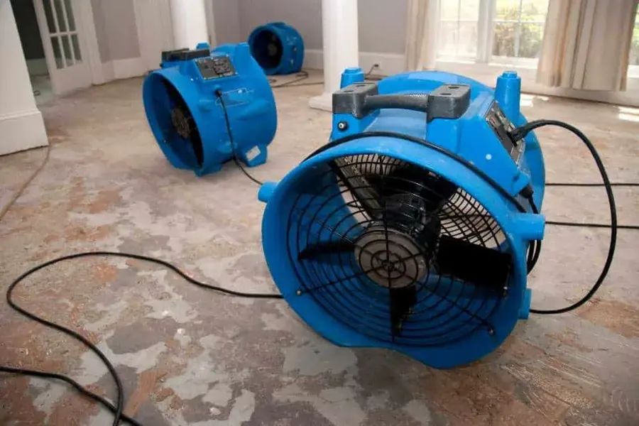 Air movers positioned across a wet floor during an interior water damage drying project