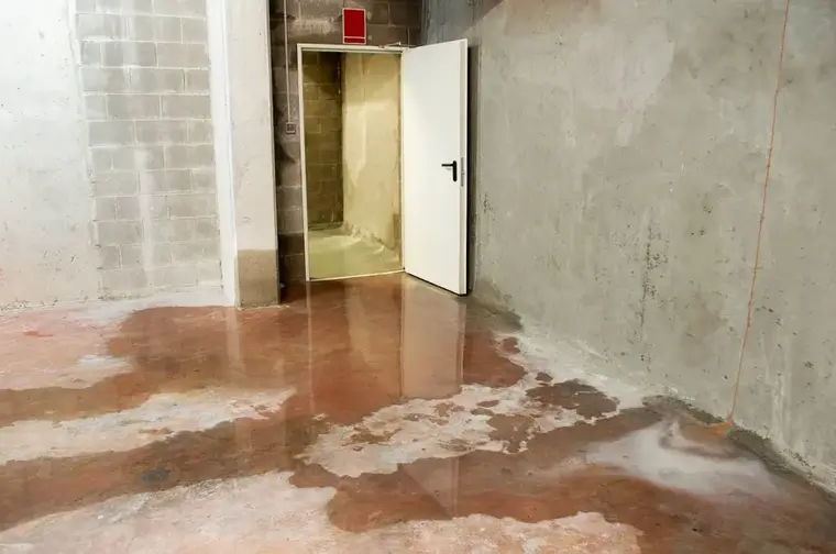 Standing water spreading across a concrete basement floor