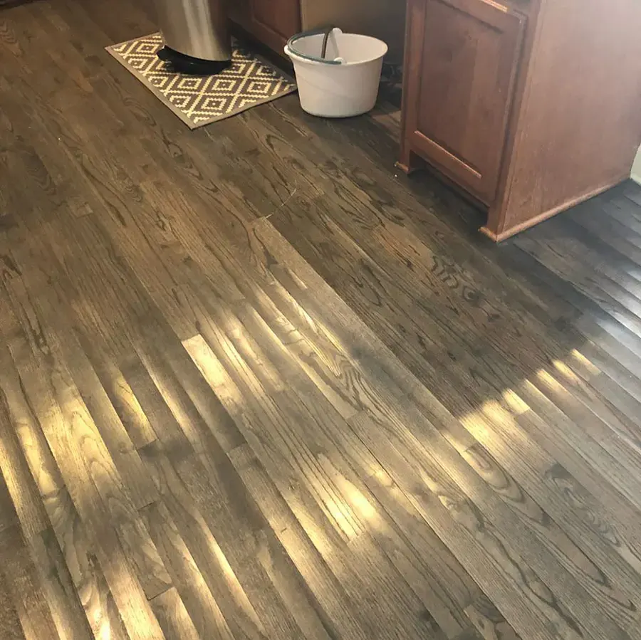 Water glistens across wood flooring beside kitchen cabinets